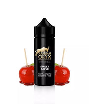 A 100ml bottle of Sweet Apple flavored ARABIAN ORYX E Liquid with a black cap, displayed alongside two apple candies on sticks. The label indicates the flavor and nicotine content of the juice.